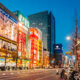 Foto retratando uma rua da grande cidade de Tóqui, cheias te telões e luzes iluminando a rua