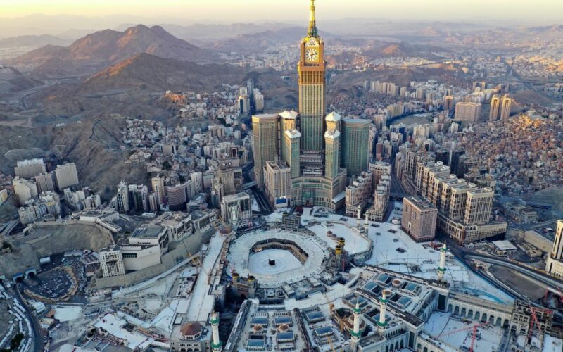 Vista do hotel Abraj Kudai em Mecca, Arábia Saudita, o maior hotel do mundo, com destaque para o grande relógio na torre central, uma combinação de arquitetura moderna e design islâmico tradicional.